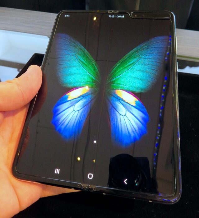 The original Samsung Galaxy Fold held open in one hand, showing the crease down the middle of its folding screen.
